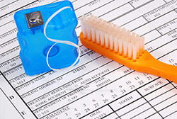 toothbrush with floss laying on a medical form
