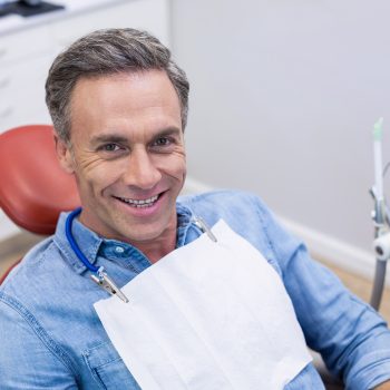 man in dentist chair smiling after receiving his new dental crown