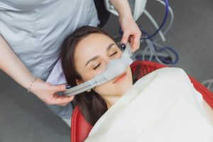 A woman receives sedation dentistry through a nasal mask